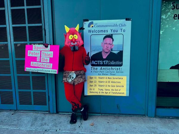 man in devil costume with anti-Thiel posters